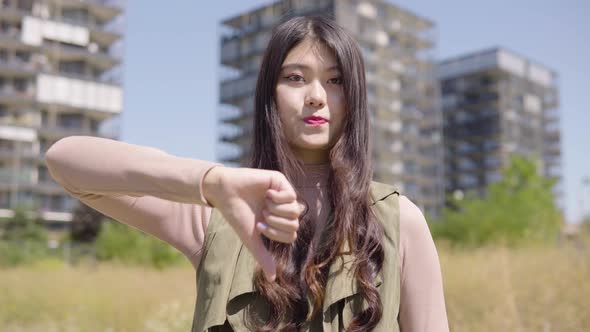 Young Asian Woman Shows Thumb Down To Camera Shakes Her Head  Apartment Building