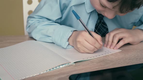 Ext CU, Tracking: Schoolboy Does Homework, Writes a Pen in a Notebook, on the Table Is a Tablet.