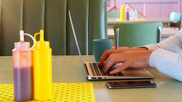 Man using laptop and mobile phone while having coffee 4k