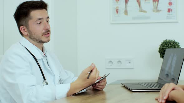 Young Male Doctor in a White Coat Examining Woman Patient at Hospital or Medical Clinic