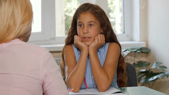 Adorable Happy Young Girl Talking To Her Teacher at Class