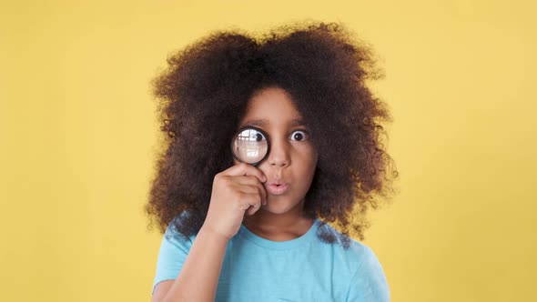 Clever, Amazed Dark-skinned Little Cutie with Magnifying Glass and Lush Curly Hair. Child Education