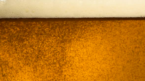 Close up pouring beer with bubbles in glass