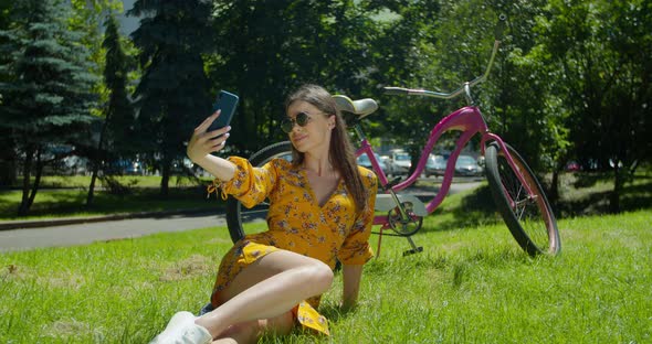 Attractive Girl Taking a Selfie on Smart Phone Sitting in the Park on the Grass. Close-up Beautiful