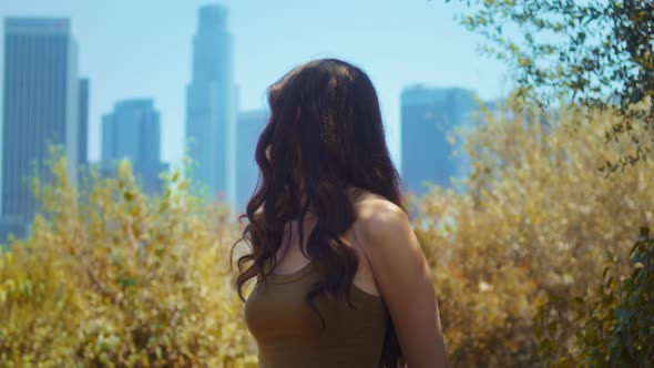 Woman Looking Back on Skyscrapers Standing in Park