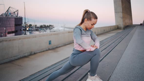 Young Athletic Female Doing Deep Lunge Exercises on Street Stairs