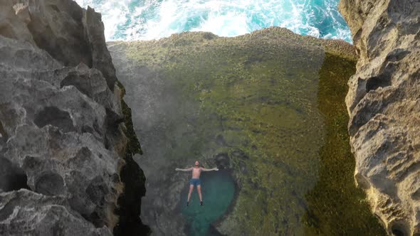 Aerial fly over of man in Angels billabong tilt up to setting sun over cliffs