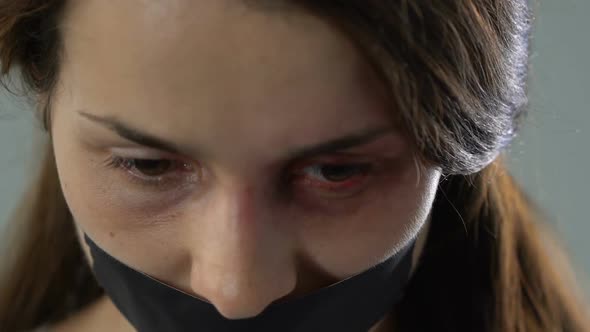 Desperate Woman With Taped Mouth Looking at Camera Human Trafficking Victim