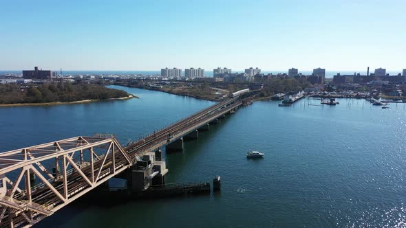 An aerial shot of a NYC subway train cross over the bay in Queens, NY. The camera dolly in towards t