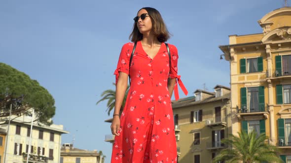 A woman walking in a red dress in a luxury resort town in Italy, Europe.