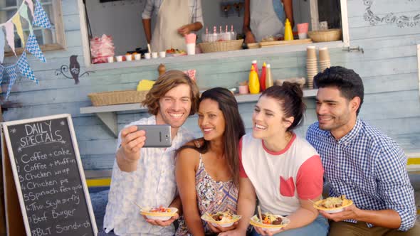 Friends taking selfie from mobile phone in food truck van