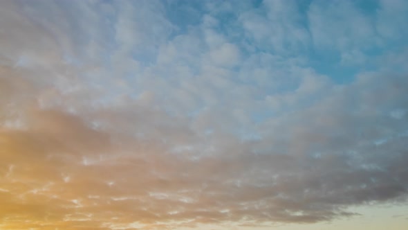 Time lapse with fast moving clouds on blue sky at sunset.