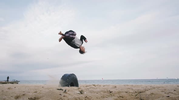 Young Man Doing Parkour Tricks on the Beach Near the Sea