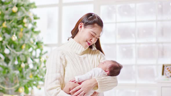 Beautiful Asian woman holding newborn baby in arms and kissing