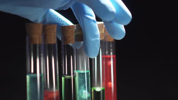 Closeup of a Gloved Hand Takes a Test Tube with Blue Liquid