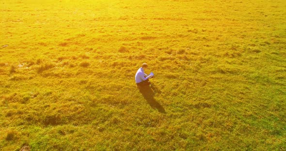 UHD Aerial View. Low Orbital Flight Over Businessman Sitting on Green Grass with Notebook Pad