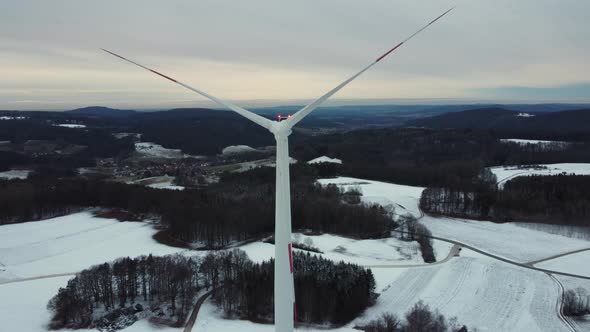 Flying above a wind turbine. Wind power plant in a winter landscape.