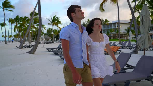 Boyfriend girlfriend dating couple takes walk on white sandy beach. Private luxurious hotel resort p