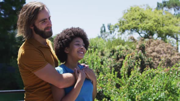 Mixed race couple embracing each other and enjoying the view while standing in the balcony at home