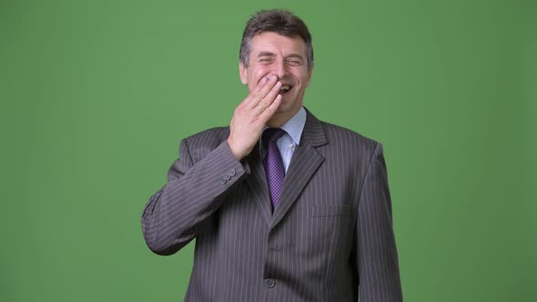 Mature Handsome Businessman Against Green Background