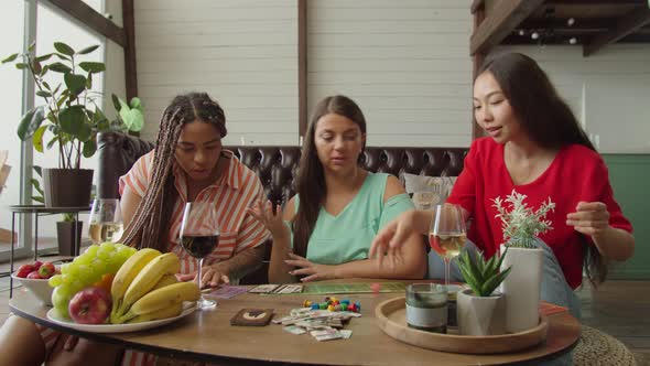 Diverse Female Friends Playing Board Game Sitting on Floor Indoors