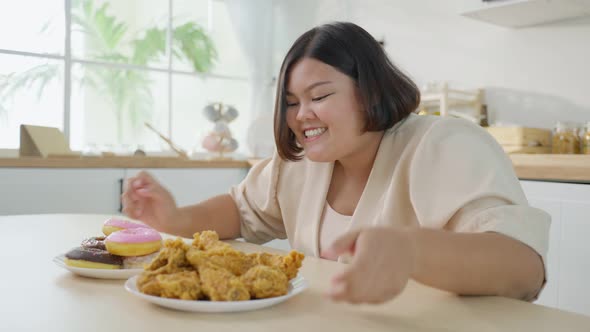 Asian young oversize big women feel happy for unhealthy foods, fried chicken and donut on plate.