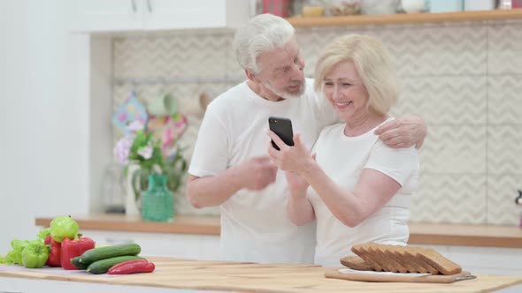 Old Couple Working on Laptop &amp; Smartphone in Kitchen