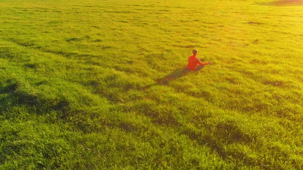 Low Altitude Radial Flight Over Sport Yoga Man at Perfect Green Grass. Sunset in Mountain