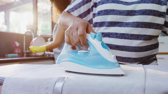 Senior woman ironing clothes in the kitchen 4K 4k