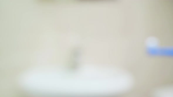 A Toothbrush with Toothpaste is Brought Into the Frame From Out of Focus Closeup