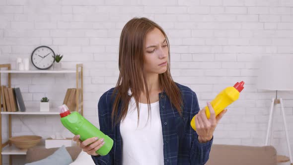 Young Housewife Comparing Two Bottles of Detergents Choosing Most Ecological and Effective