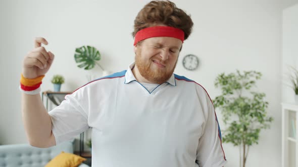 Slow Motion of Silly Guy Playing with Sports Headband Then Showing Fool Hand Gesture Indoors at Home