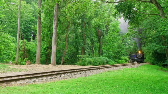 View of An Antique Steam Engine Approaching Around a Curve Traveling Thru The Woods