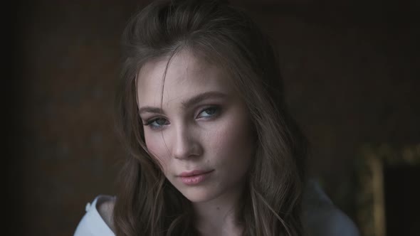 Portrait of an Attractive Girl in a White Blouse Close-up. Beautiful Blue-eyed Model Looking Into