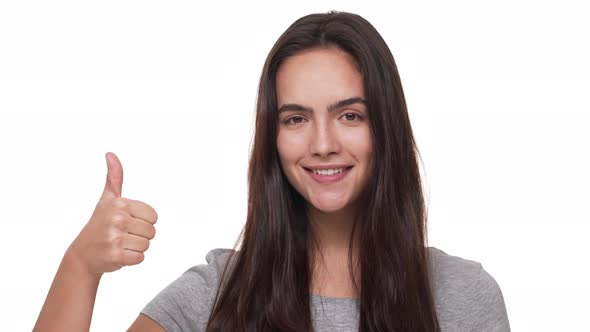 Portrait of Pleased Brunette Woman with Long Hair Looking at Camera Smiling Showing Thumb Up Over