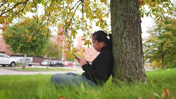 Asian woman typing and slide the screen on smartphone at the park in Autumn