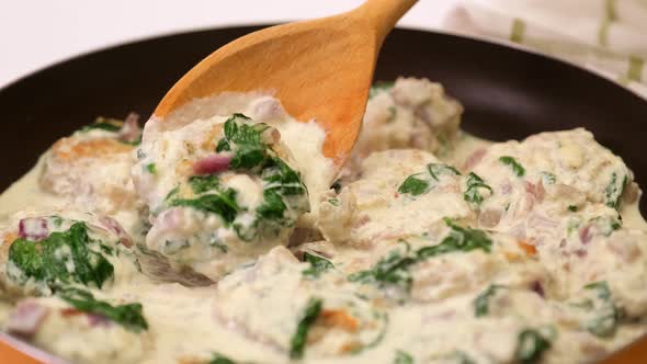 Delicious Small Meatballs with Spinach in a Creamy Sauce in the Frying Pan