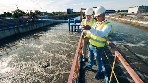 Wastewater Operators Taking a Water Sample at a Sewage Cleaning Reservoir