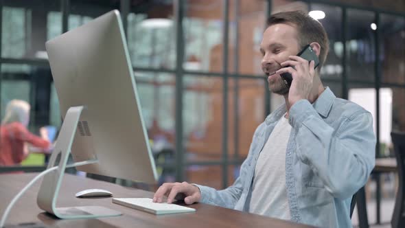 Young Man Talking on Phone at Work