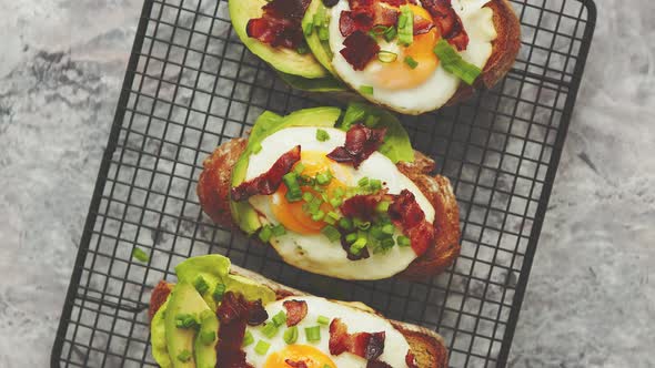 Tasty Delicious Homemade Toasts with Fried Egg, Bacon, Avocado, Lettuce and Chive