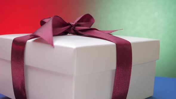 White Festive Box with Purple Ribbon and Bow on Top Rotates