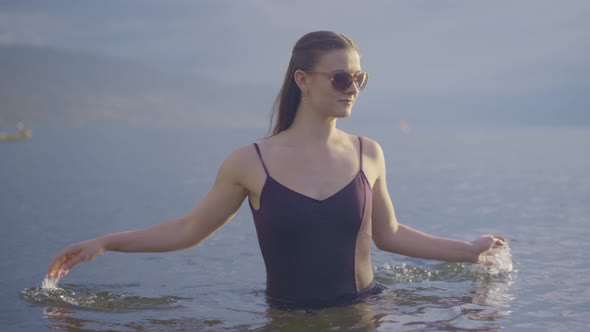 Young attractive girl in sunglasses splashing in the water