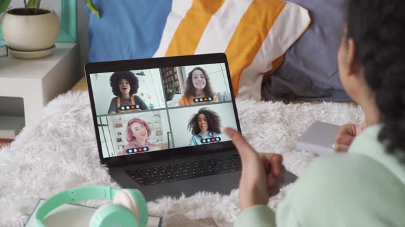 African Teen Girl Talking To Friends in Virtual Group Chat on Laptop in Bed