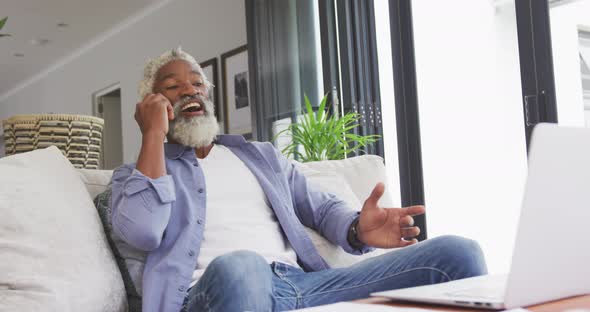 Video of african american senior man using smartphone and laptop