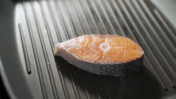 Cook Puts Steak Raw Salmon Fillet on the Grill Grate