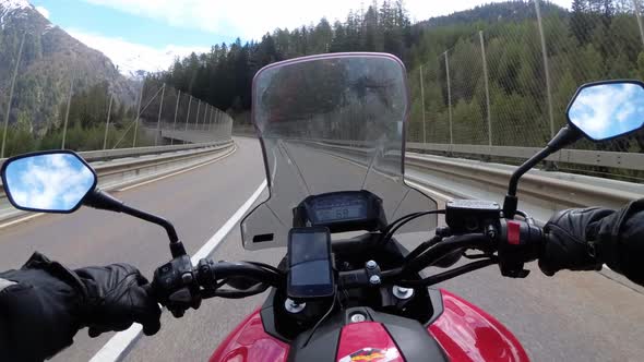 Motorcyclist Rides on Beautiful Landscape Mountain Road Near Snowy Switzerland Alps