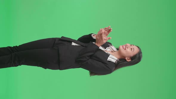 Side View Of An Asian Business Woman Clapping Her Hands In The Green Screen Studio