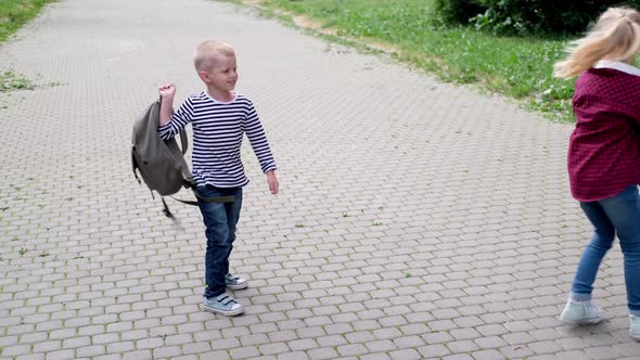 Back to School Children Playing on Street Blonde Boy and Girl Spinning with Backpacks