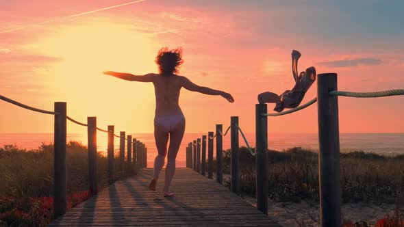 Young Sexy Woman Silhouette in a Wooden Foot Bridge at the Beach at Sunset