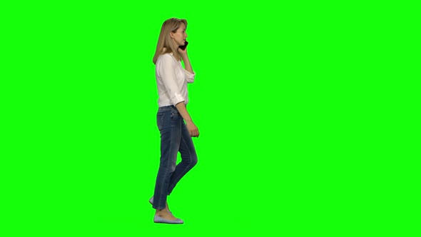 Blonde Woman Is Calmly Walking and Talking on the Mobile Phone on Green Screen. Chroma Key, Shot